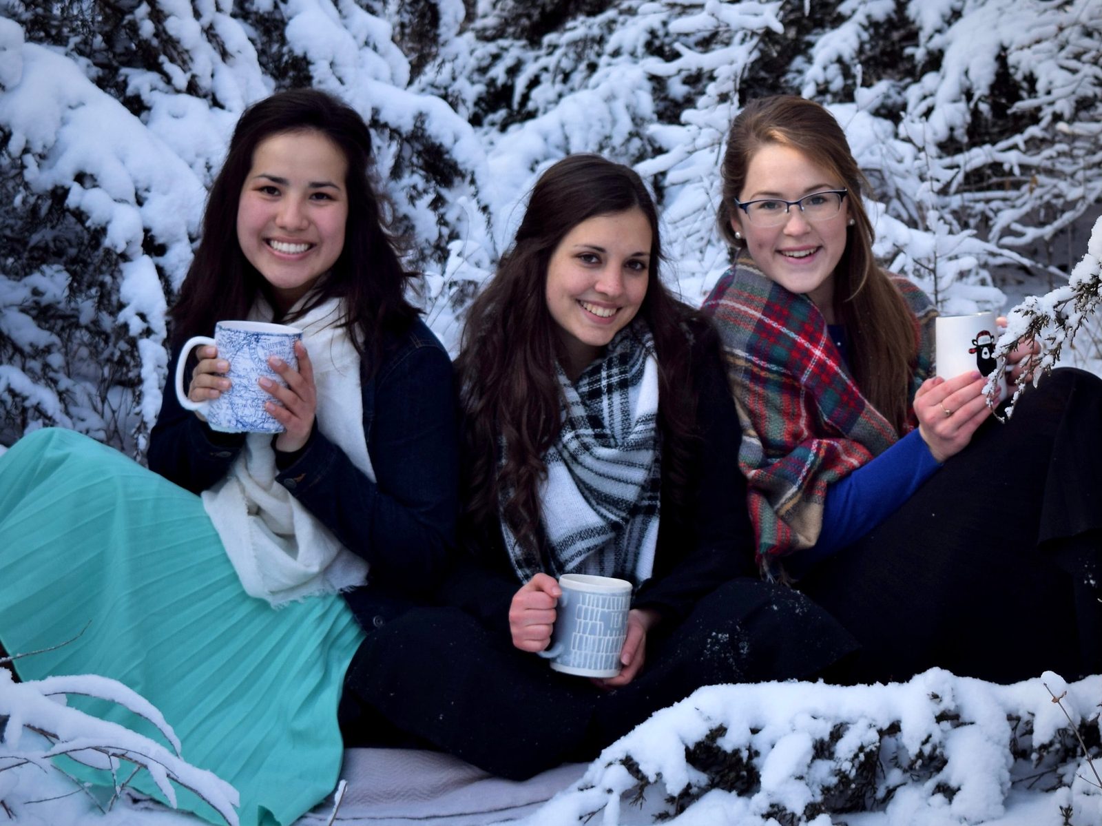 The three of us in winter scarves, holding mugs in the snow